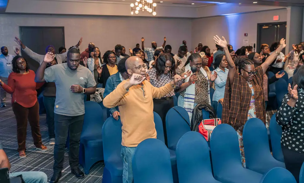 The whole room standing in worship with hands raised