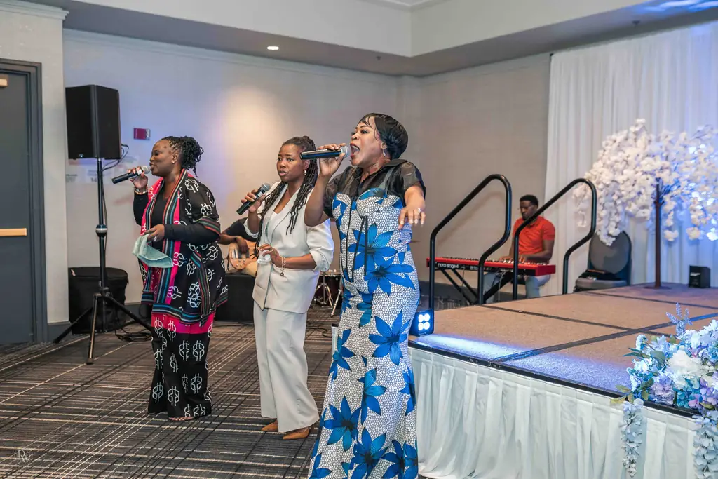 Three women singing together on stage
