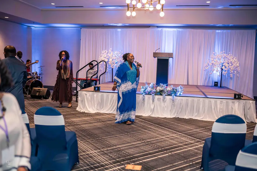 A worship leader singing on stage in a bright room at the ministry’s 5th anniversary revival
