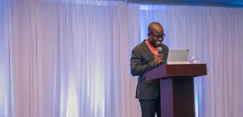 Pastor Fred Asante smiling as he speaks at the pulpit