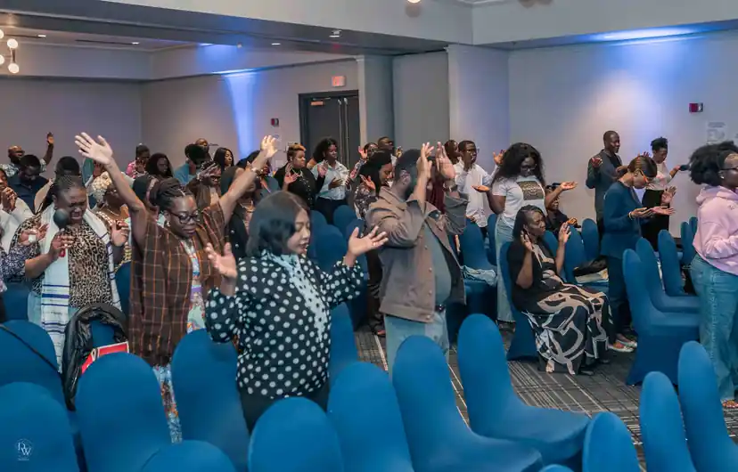 The congregation standing in worship with hands raised
