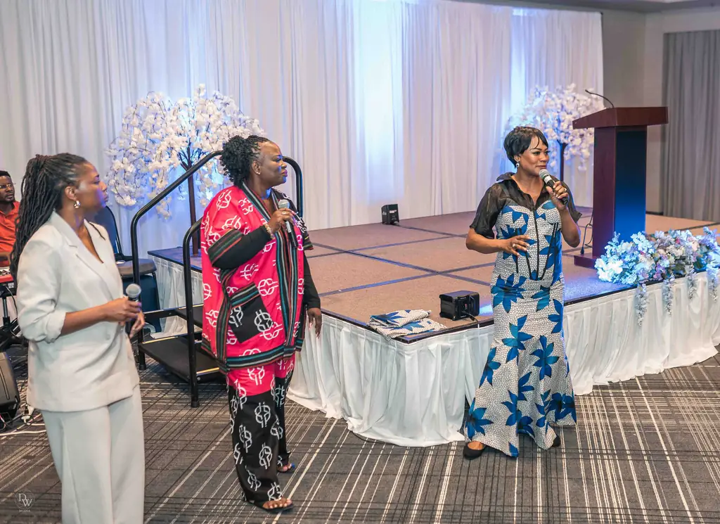 Three women singing together on stage